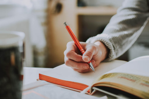 a person writing on a notebook using a pen