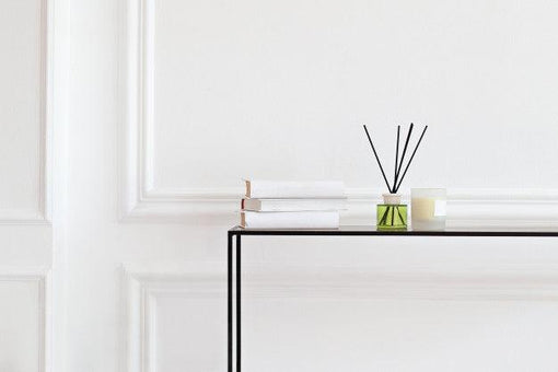 a shelf with books and reed diffuser on top